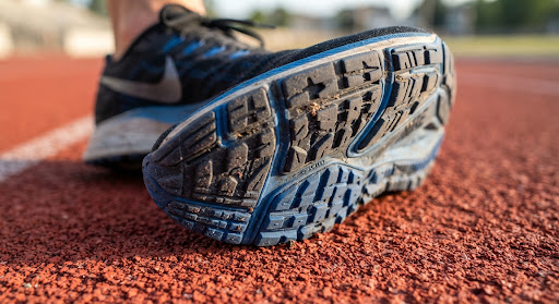 Close-up of a running shoe sole with tread grooves on a red running track